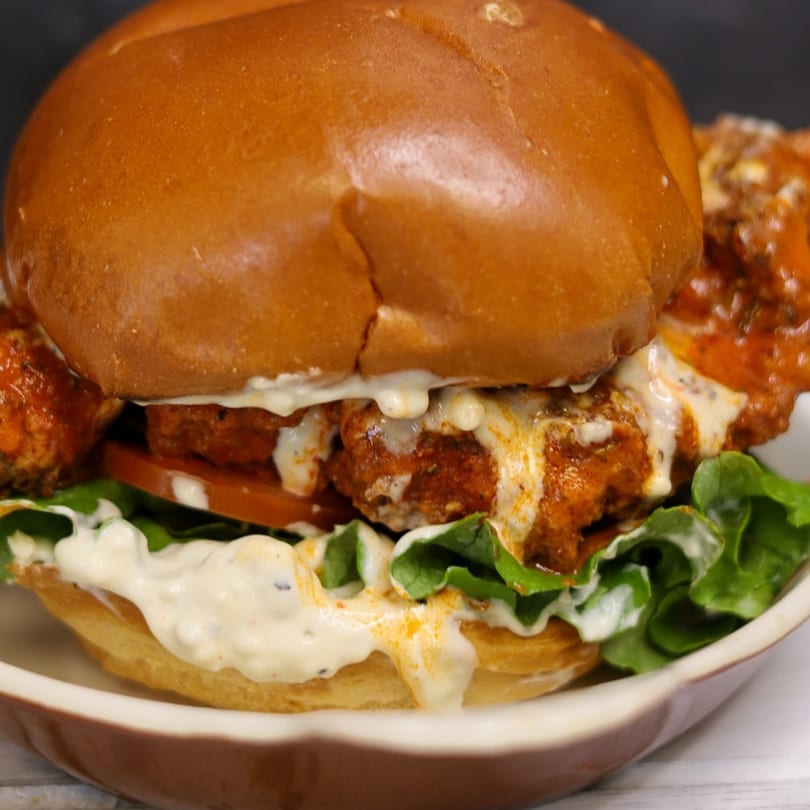 Big Dogs' spicy chicken sandwich with lettuce, tomato, and creamy sauce on a brioche bun.