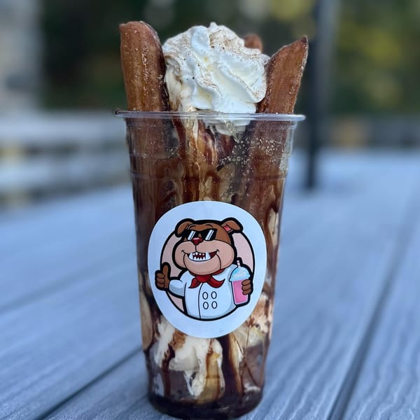 Big Dogs' chocolate sundae with whipped cream, cinnamon, and churros, featuring the bulldog logo.