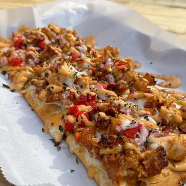 Loaded fries from Big Dogs, topped with chicken, cheese, red peppers, onions, and sauce.